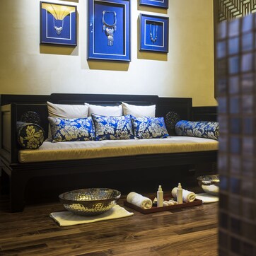 A room with a bed, framed jewelry, and a tiled wall.