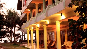 A hotel with a covered outdoor seating area, multiple floors, and a well-lit entrance. - Time N Tide Beach Resort (Hikkaduwa)