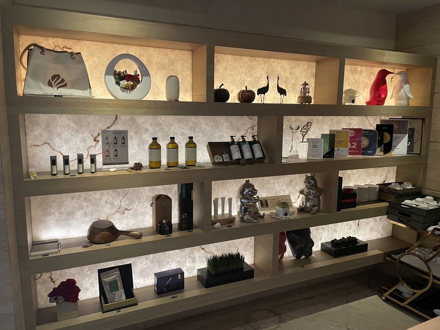 A well-lit display of various items including bottles, figurines, and decorative objects on shelves.