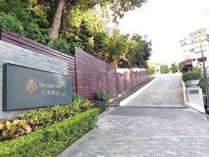The Gaia Hotel entrance with a brick wall, wooden fence, and a paved pathway leading to the building. - The Gaia Hotel Taipei (Taipei)