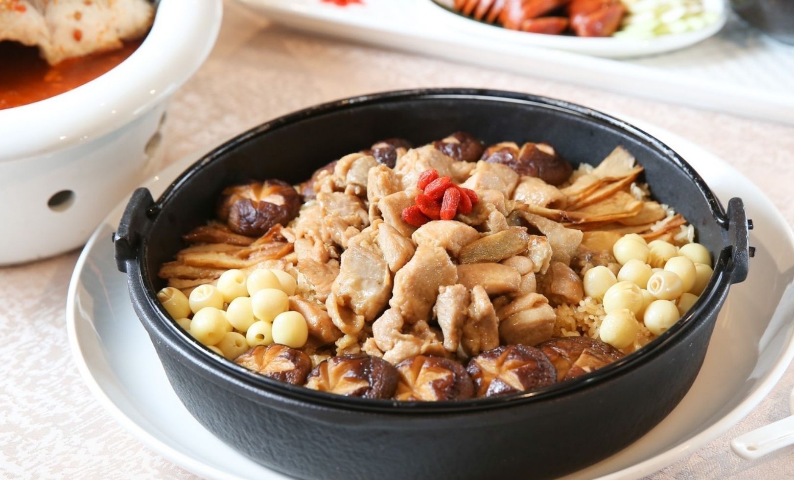A bowl of Qiyan One - Black Sesame Oil Chicken Rice with peanuts and red dates.