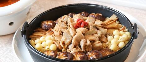 A bowl of Qiyan One - Black Sesame Oil Chicken Rice with peanuts and red dates.