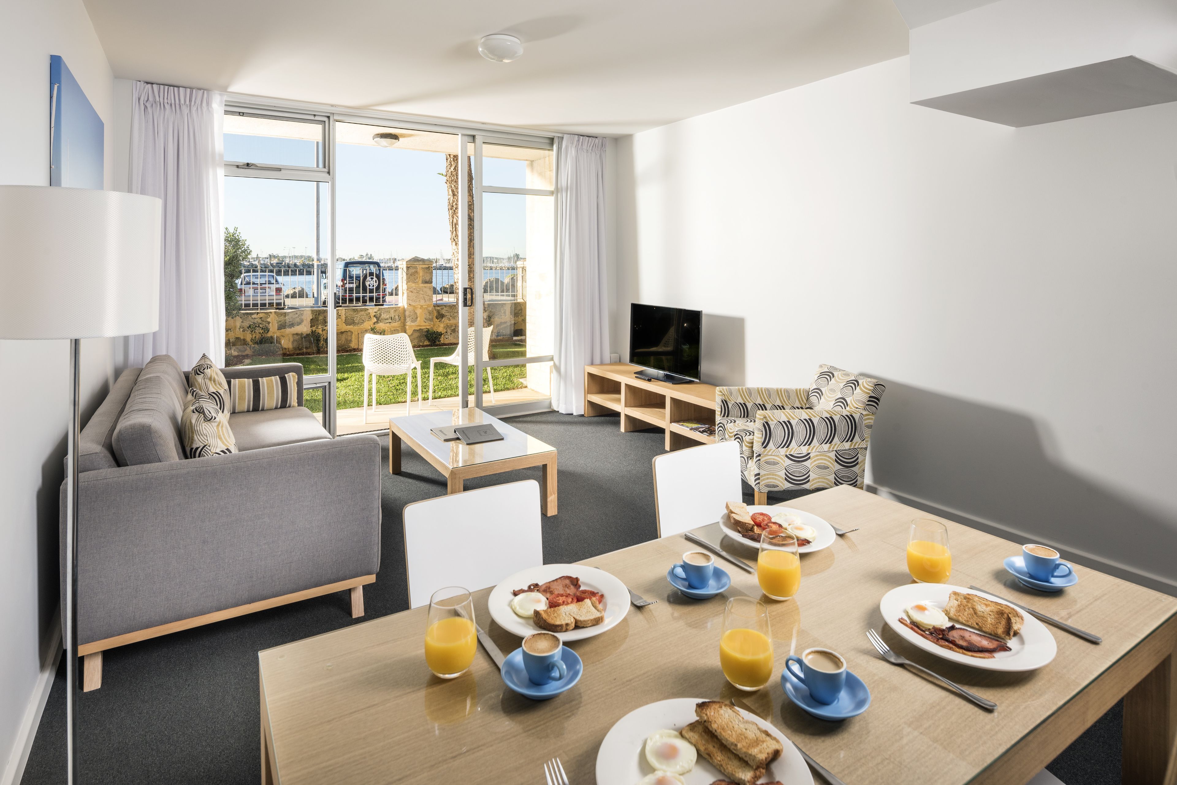 Habitació d'hotel moderna amb zona de menjador, sofà i un balcó amb vistes.