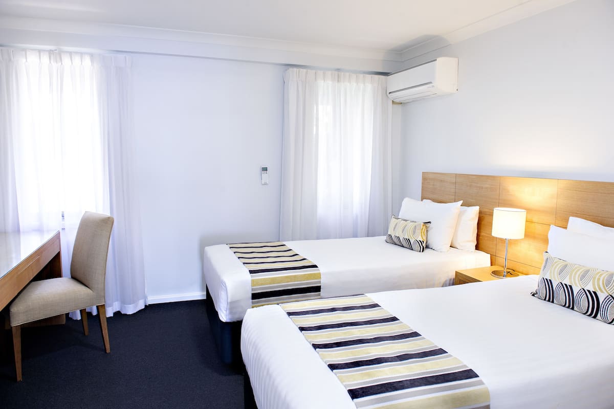 Habitación de hotel con dos camas, un escritorio y una silla.