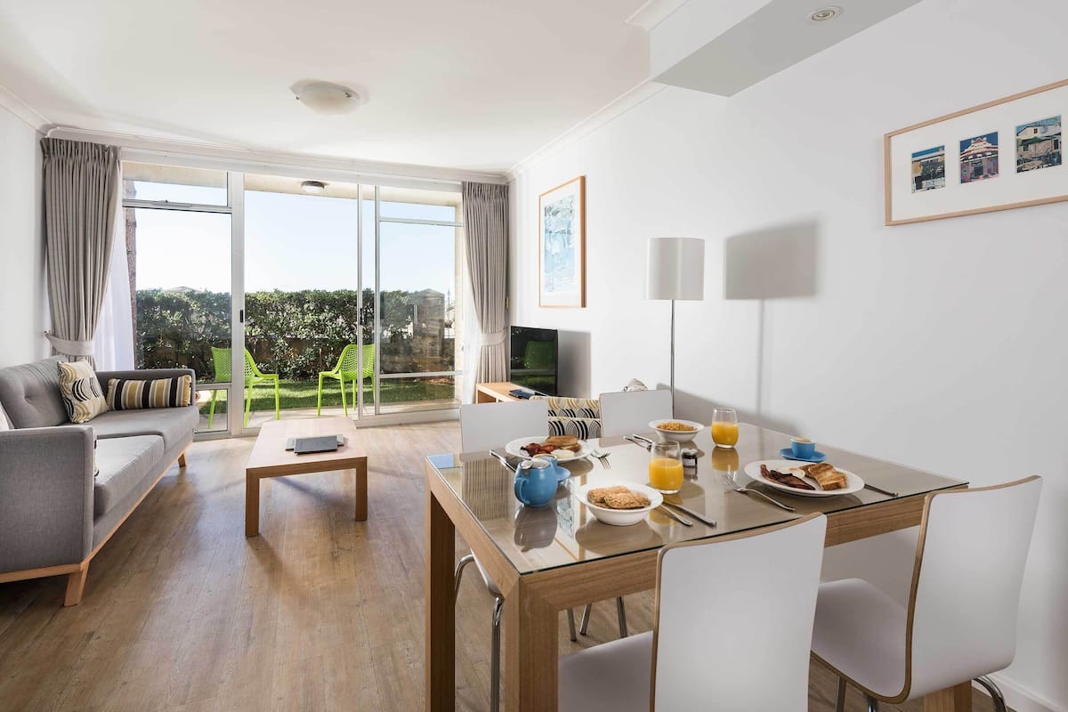 Una sala de estar moderna con un sofá, una mesa de comedor con desayuno y un televisor.