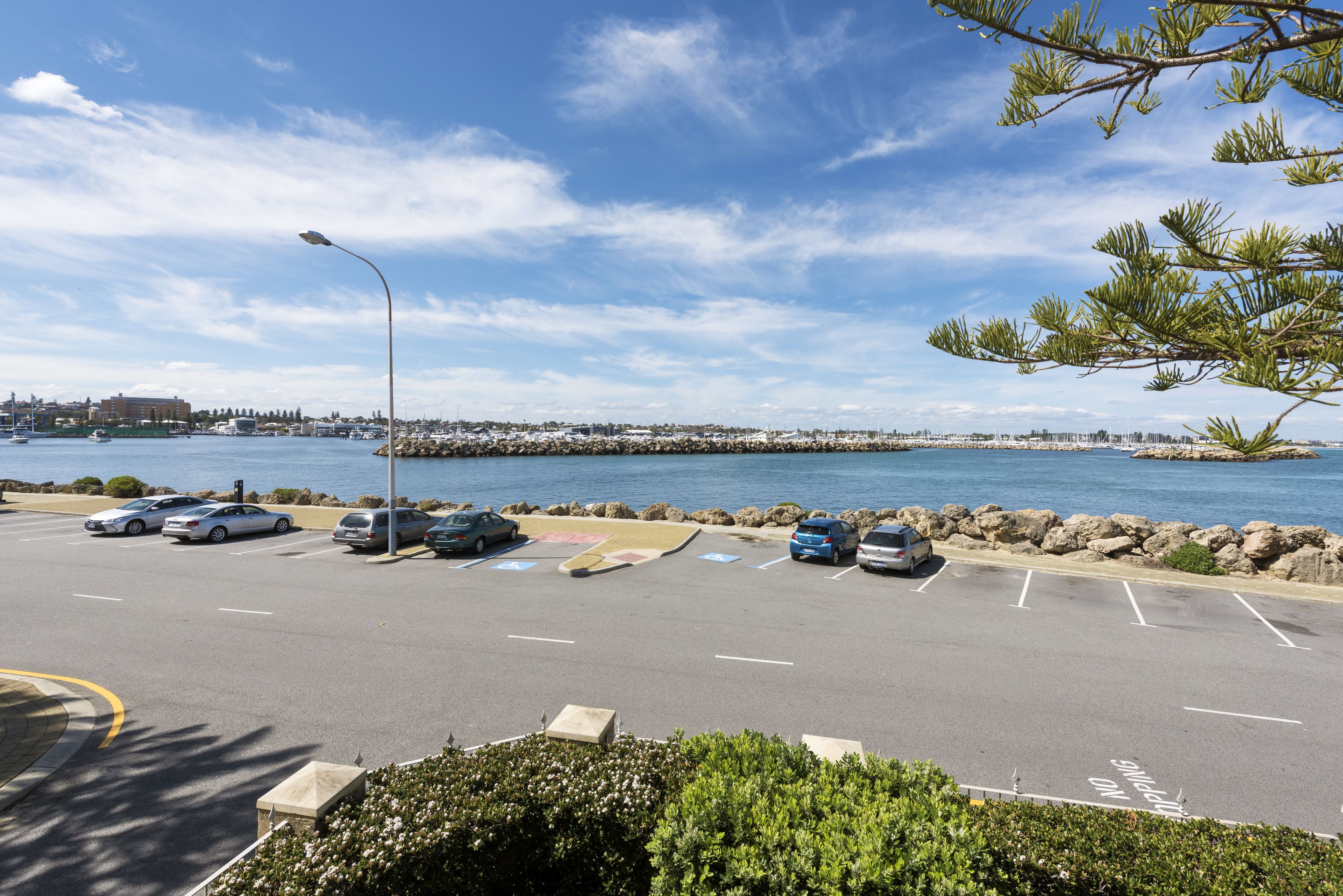 A parking lot with cars, a clear sky, and a body of water in the background.