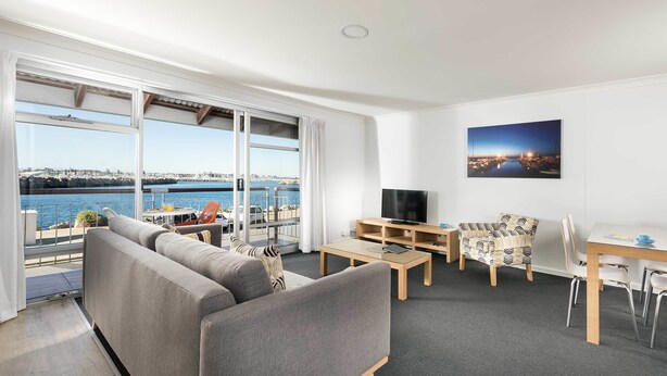 A modern living room with a large window, a sofa, a TV, a small table, and a chair. - Be. Fremantle (Fremantle)