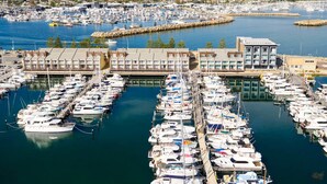 A marina with numerous boats docked, a large building with multiple balconies, and a view of the surrounding town. - Be. Fremantle (Fremantle)