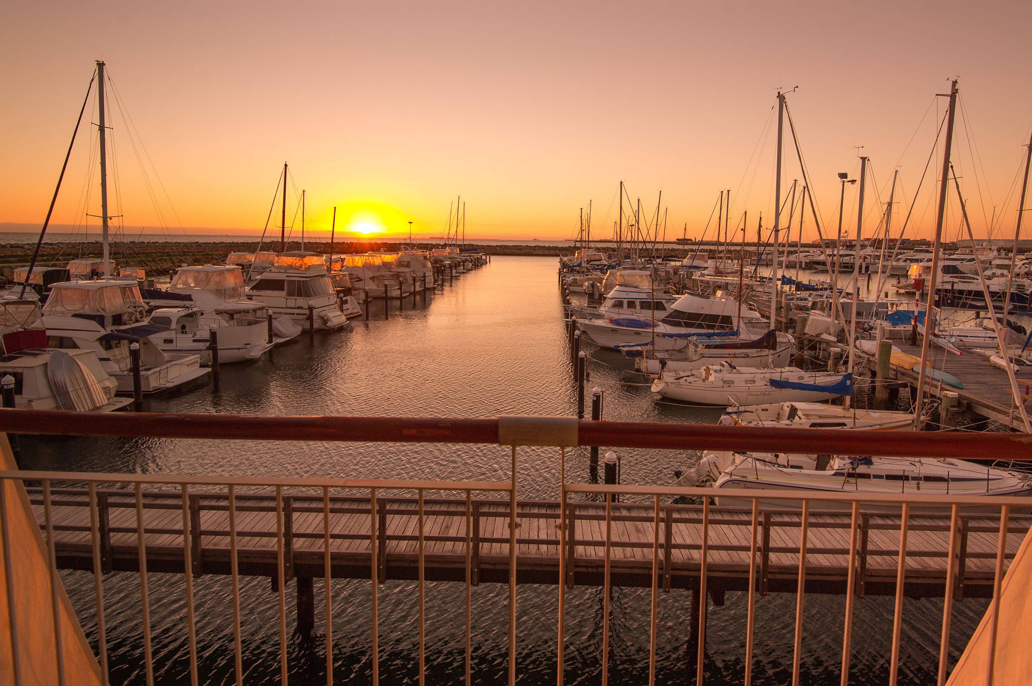 Un puerto deportivo con barcos amarrados a muelles de madera al atardecer.