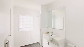 Ein modernes Badezimmer mit Waschbecken, Spiegel und Duschkabine aus Glas.