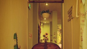 Un pasillo con una puerta de madera, una valla de madera a cada lado y una maceta colgante con flores.