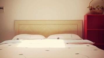 A bed with a wooden headboard, white bedding, and a basket on a red shelf beside it.
