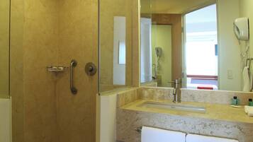 A bathroom with a glass-enclosed shower, a sink with a towel hanging, and a mirror reflecting the room.
