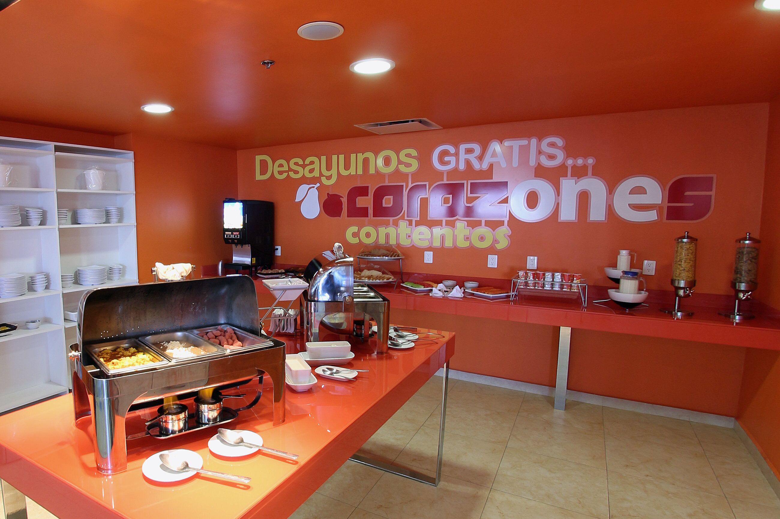 Montaje de buffet con diversos alimentos y un letrero que dice 'Desayunos GRATIS... corazones'.