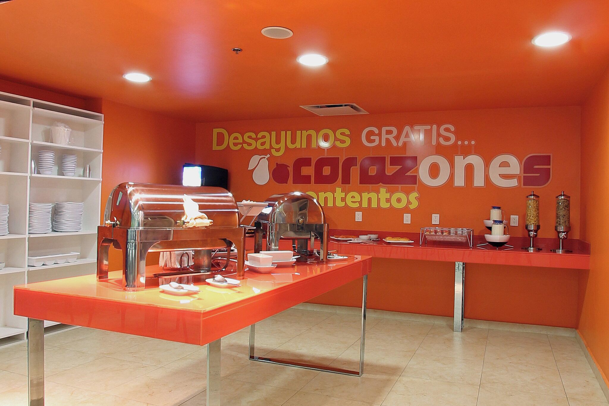A breakfast station with a buffet setup, including a coffee machine and various food containers.