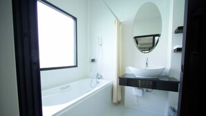 Un baño moderno con bañera, lavamanos y un espejo grande.