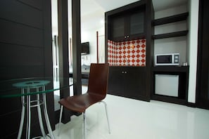 A modern kitchen with a glass table, a brown chair, and a microwave.
