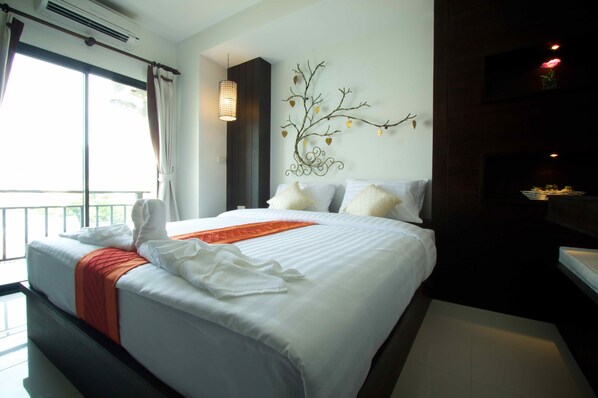 Quarto de hotel com uma cama grande, um objeto decorativo na parede e vista para o exterior.