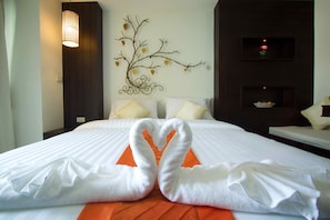 A hotel room with a bed, a decorative wall piece, and a shelf with a vase.