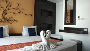 Una habitación de hotel con cama, espejo montado en la pared y diseño decorativo de árbol.