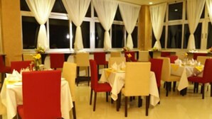 A restaurant with tables and chairs, white tablecloths, and red chairs. - Nazra Hotel (Addis Ababa)