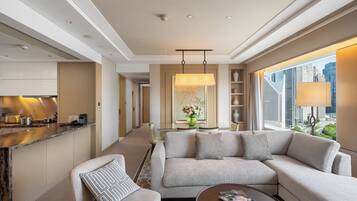 A modern hotel room with a living area, a kitchen, and a large window with a city view.