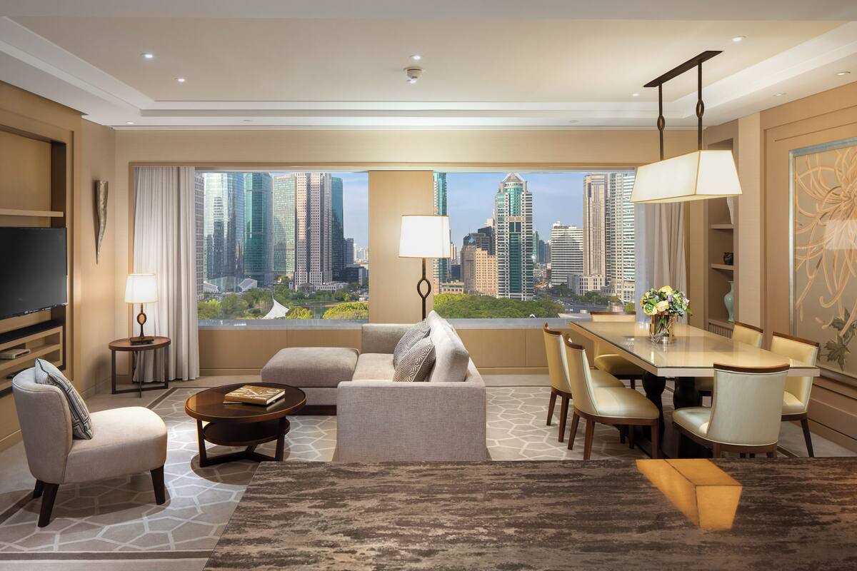 Una habitación de hotel moderna con vista a la ciudad, televisión de pantalla plana, zona de comedor y sofá.