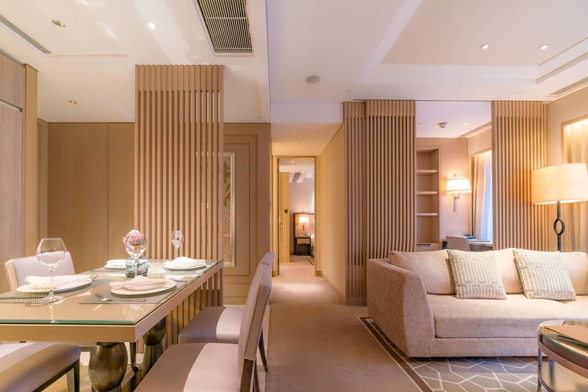 Una habitación de hotel moderna con zona de comedor, sofá y lámpara.