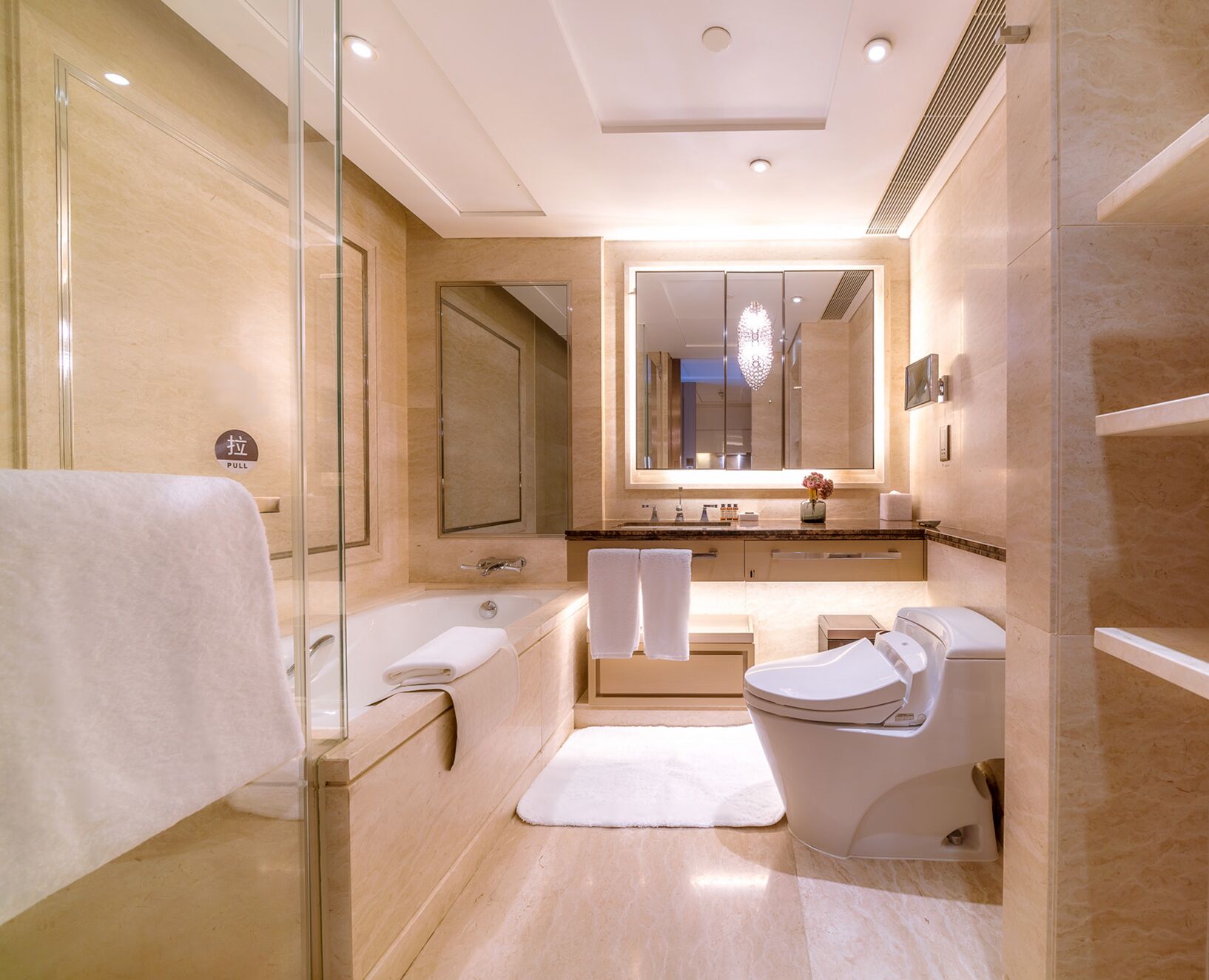 Een moderne badkamer met een douchecabine van glas, een bad, een toilet en een wastafel met spiegel.