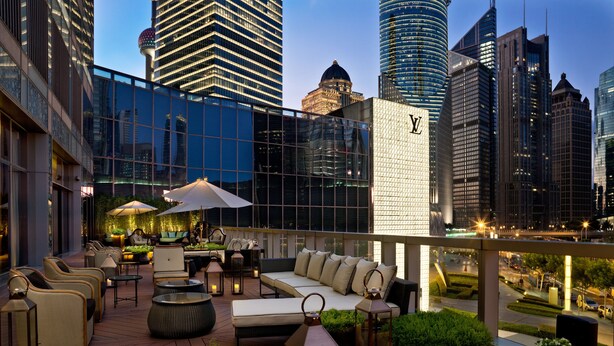 A rooftop lounge with outdoor seating, a view of the city skyline, and a Louis Vuitton store in the background. - IFC Residence (Shanghai)