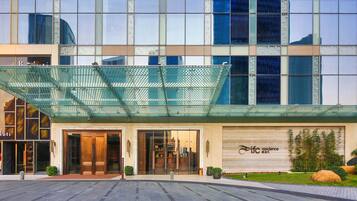 Una entrada de hotel moderna con fachada de vidrio, un área de acceso cubierta y un letrero que dice "ITFC Residence".