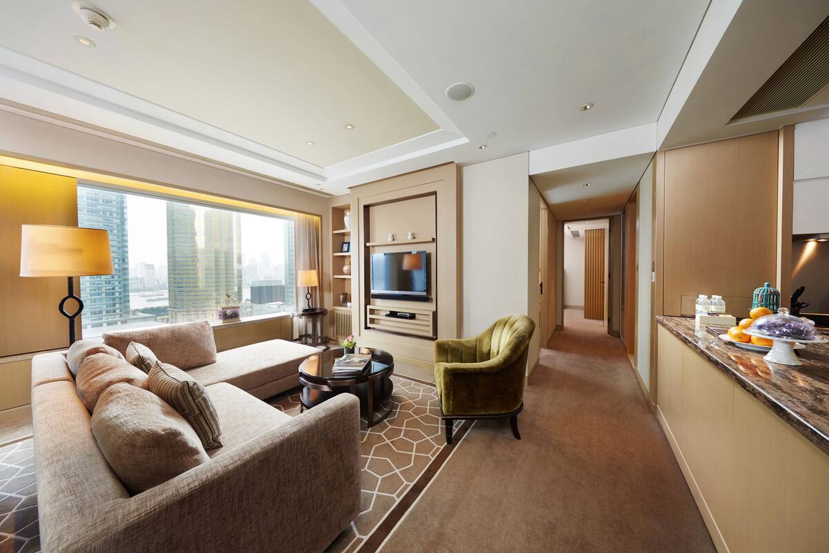 Una habitación de hotel moderna con sofá, sillón y zona de comedor.