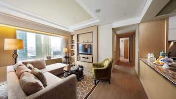 A modern hotel room with a sofa, armchair, and dining area.