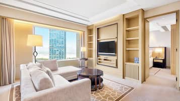 A modern hotel room with a sofa, two lamps, a TV, and a view of a cityscape.