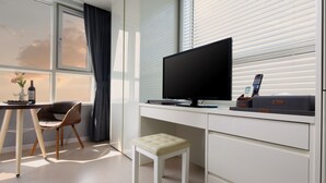 A modern room with a desk, a chair, a small stool, a television, and a window with curtains. - Shinchon Ever8 Serviced Residence (Seoul)