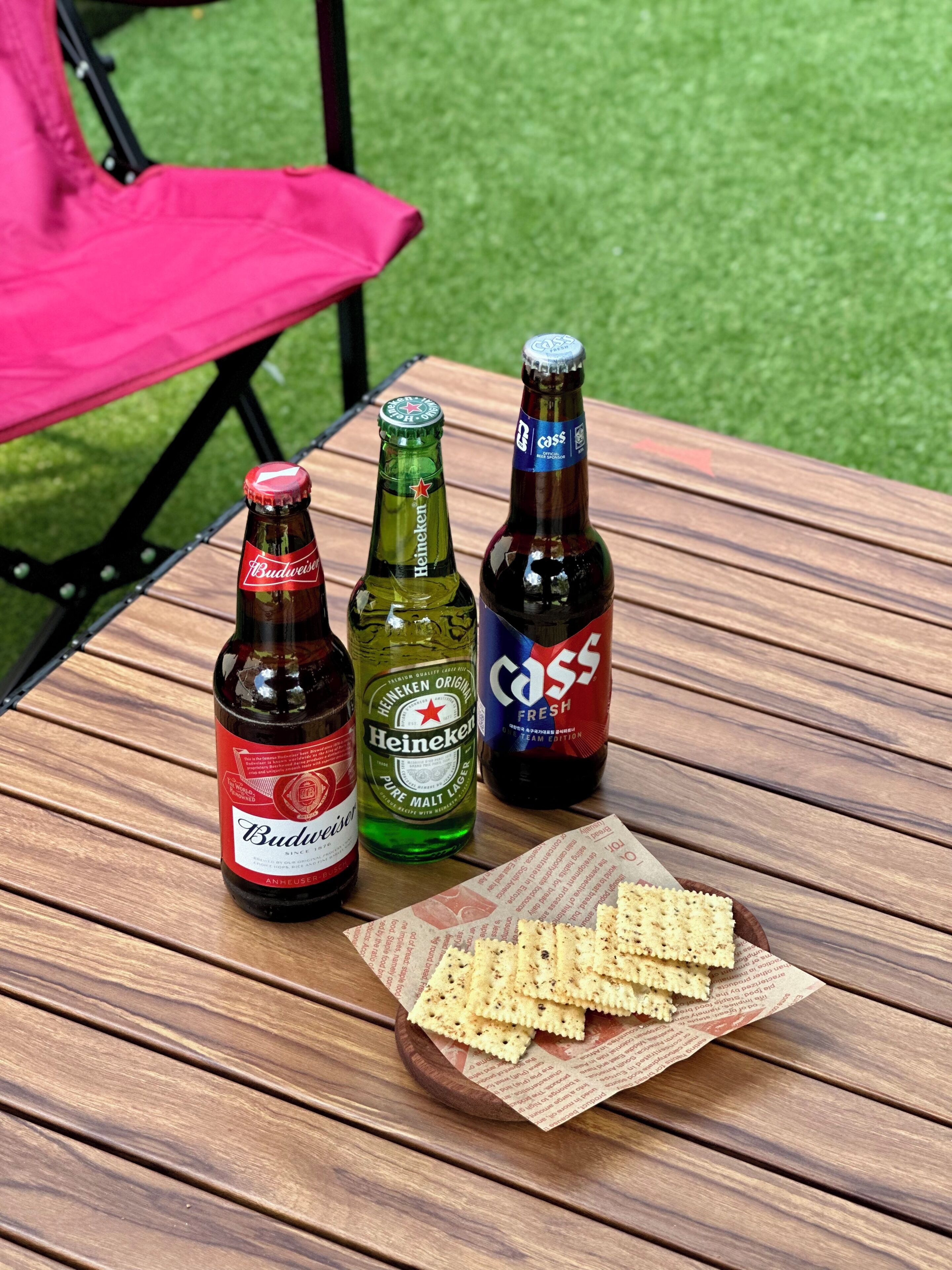 Una mesa con tres botellas de cerveza y un plato de galletas.