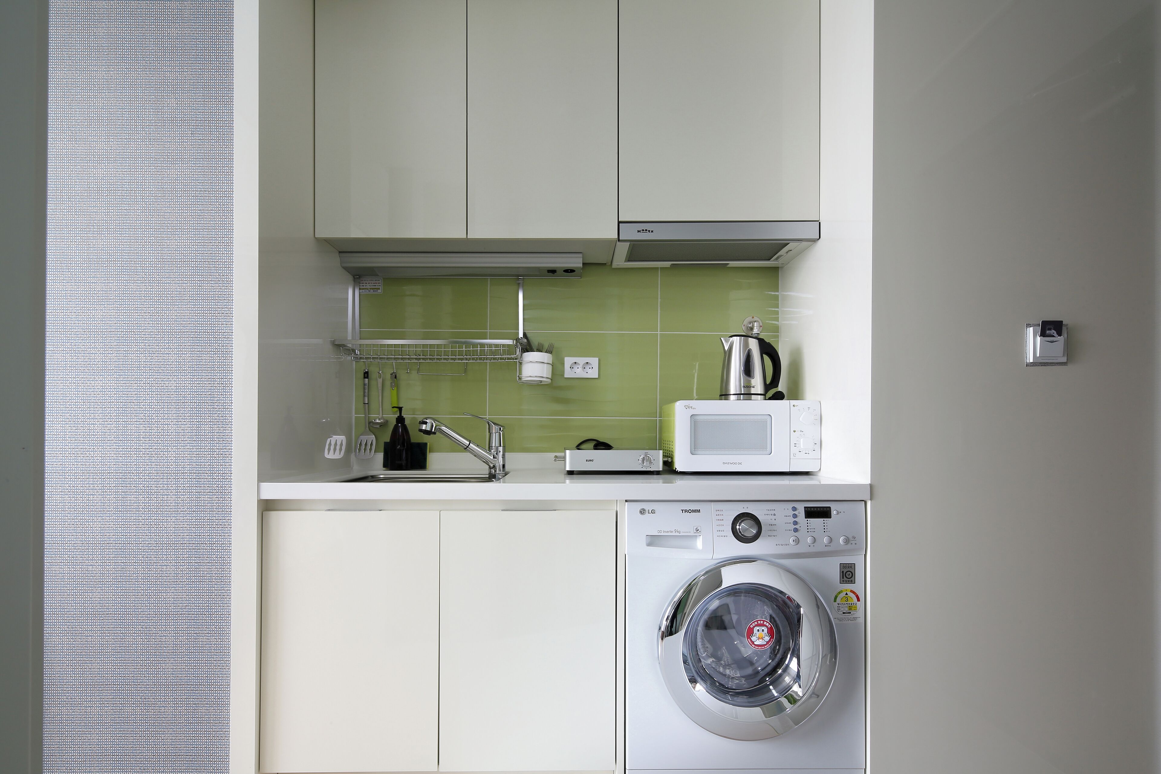 A compact kitchen with a washing machine, a microwave, and a sink.
