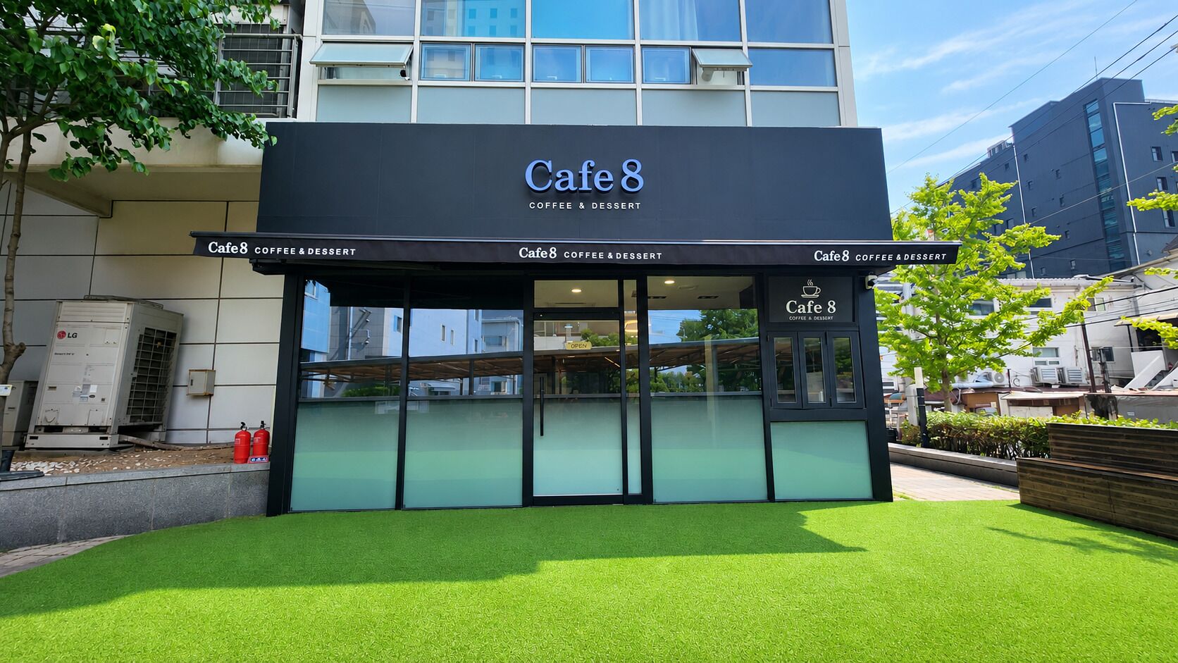 Un edificio con un letrero que dice 'Cafe 8 Coffee & Dessert' y fachada de vidrio.