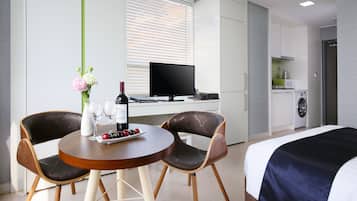 Una habitación de hotel moderna con una cama, una mesa de comedor con sillas, un televisor y una cocina.