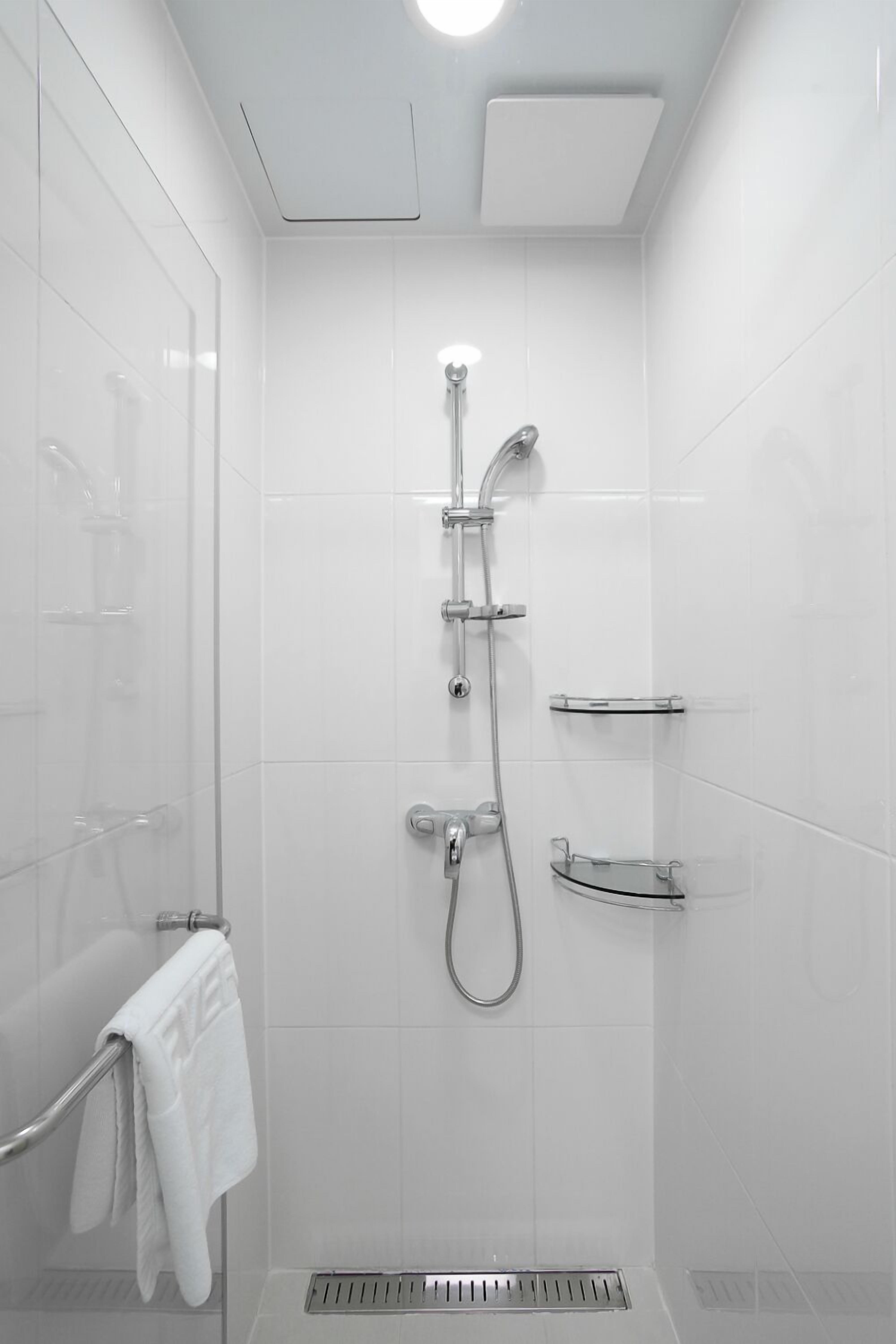 A modern shower with a glass enclosure, a handheld showerhead, and a wall-mounted faucet.