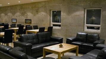 A conference room with black leather sofas, wooden tables, and framed pictures on the walls.