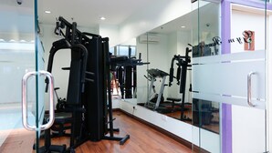 Uma academia com equipamentos de exercício, um espelho grande e piso de madeira.