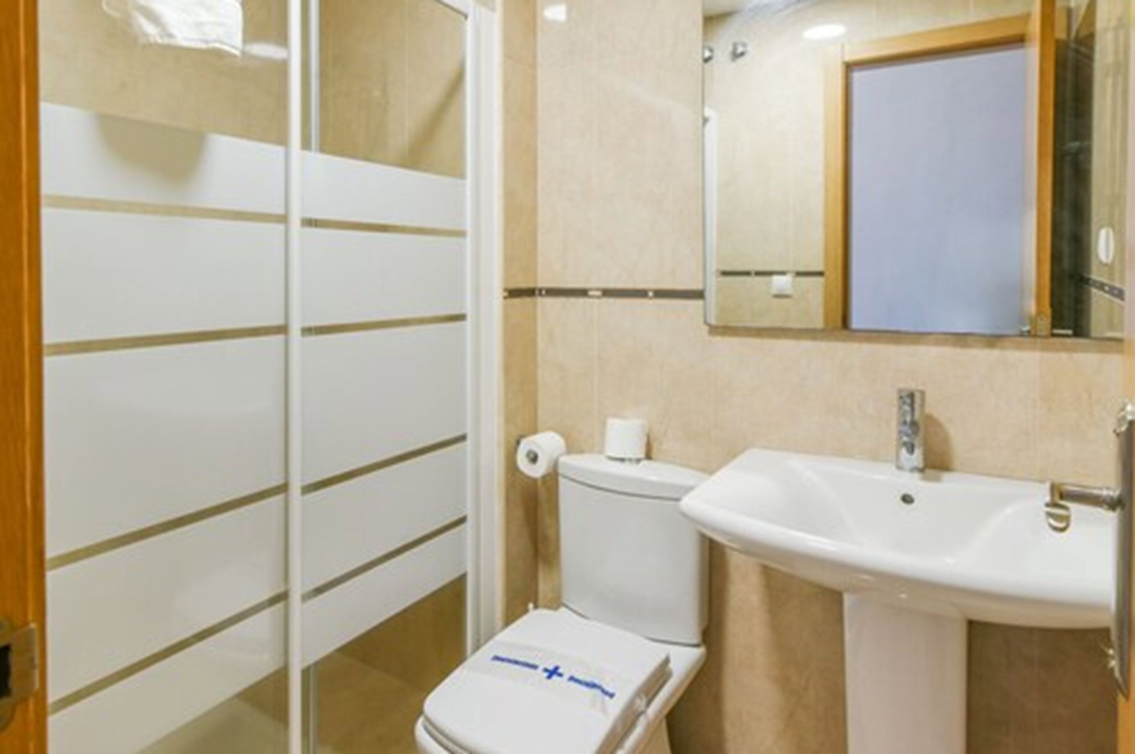 Un baño con inodoro, lavamanos y espejo.