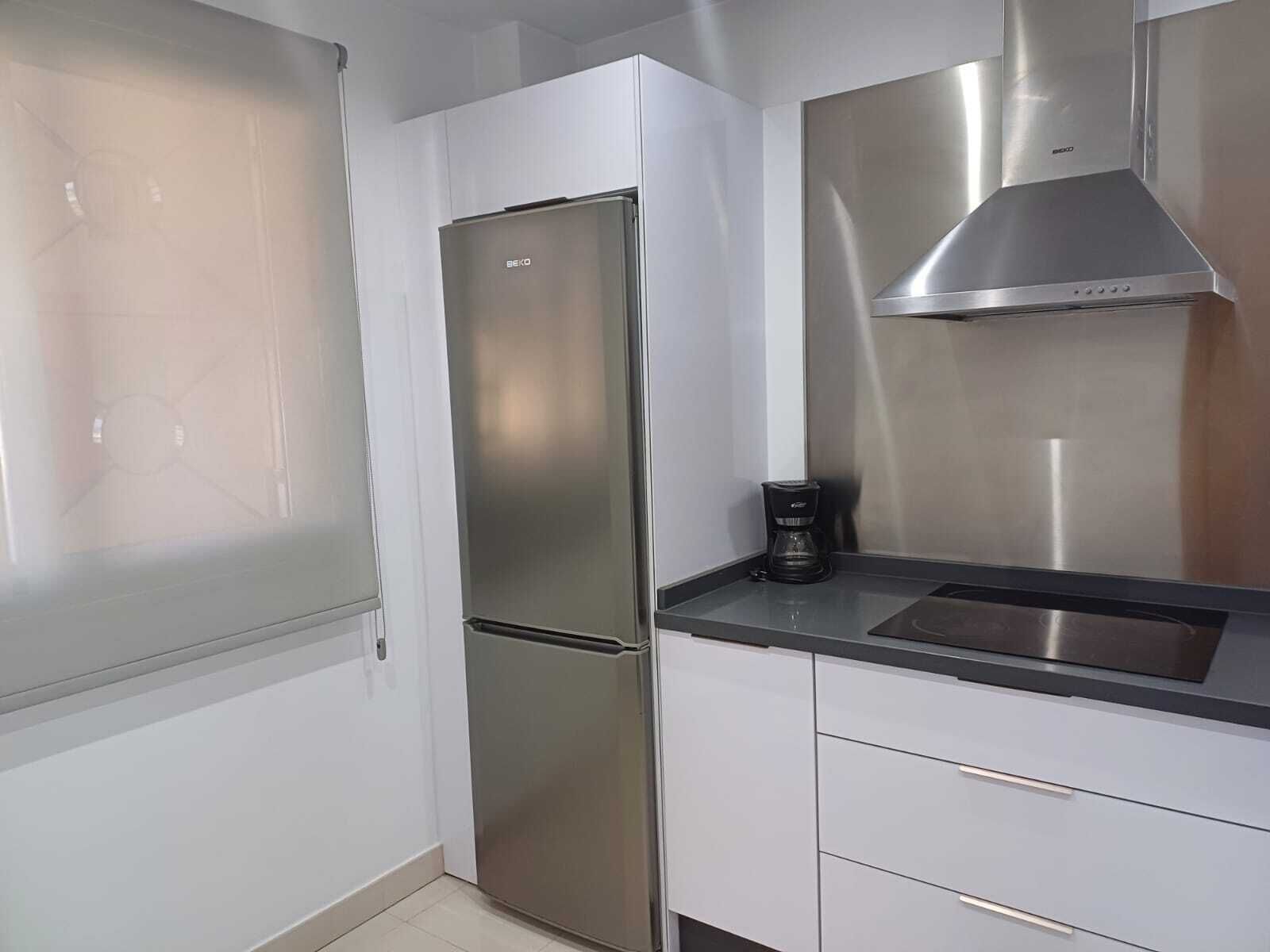 A modern kitchen with a stainless steel refrigerator, a coffee maker, and a stainless steel range hood.