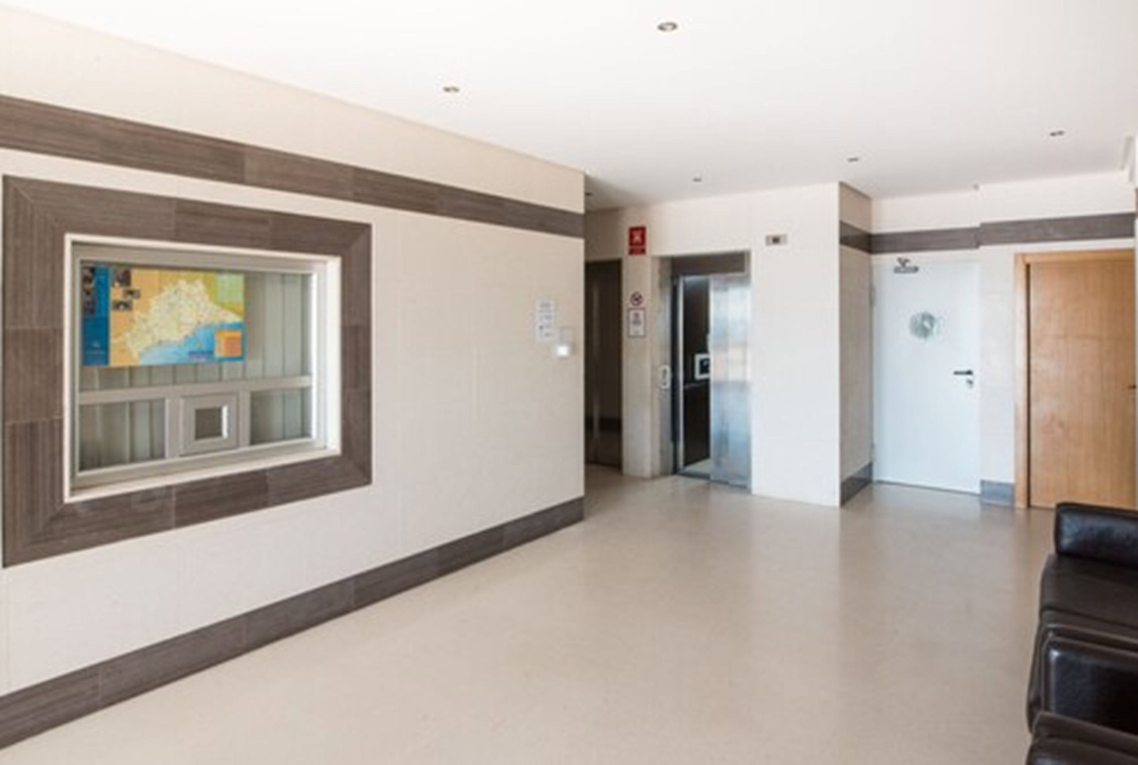 A hallway with a map on the wall, a fire alarm, and a door.