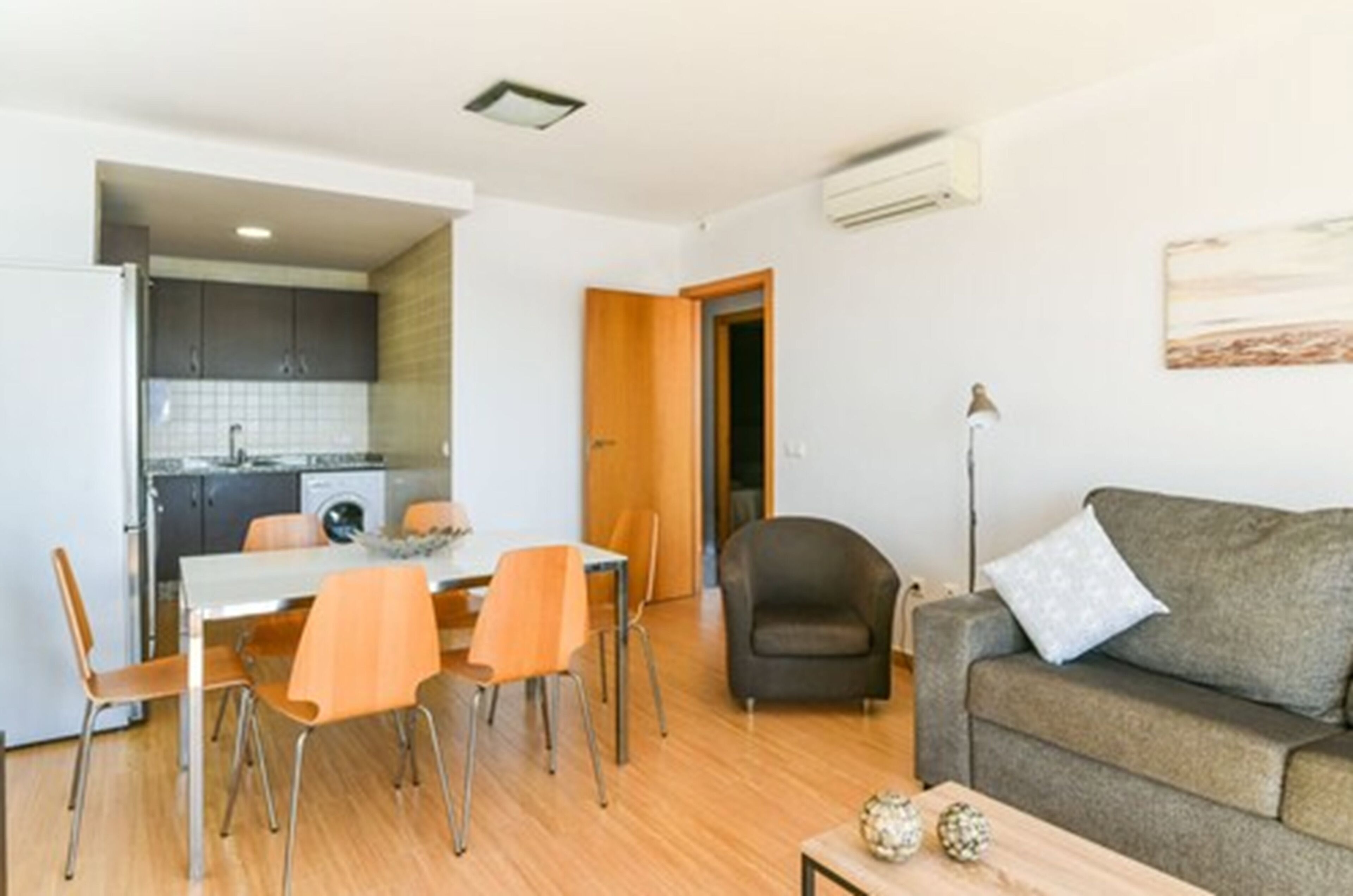 A compact living space with a dining area, a sofa, and a kitchenette.