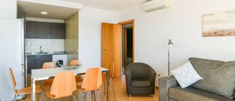 A compact living space with a dining area, a sofa, and a kitchenette.