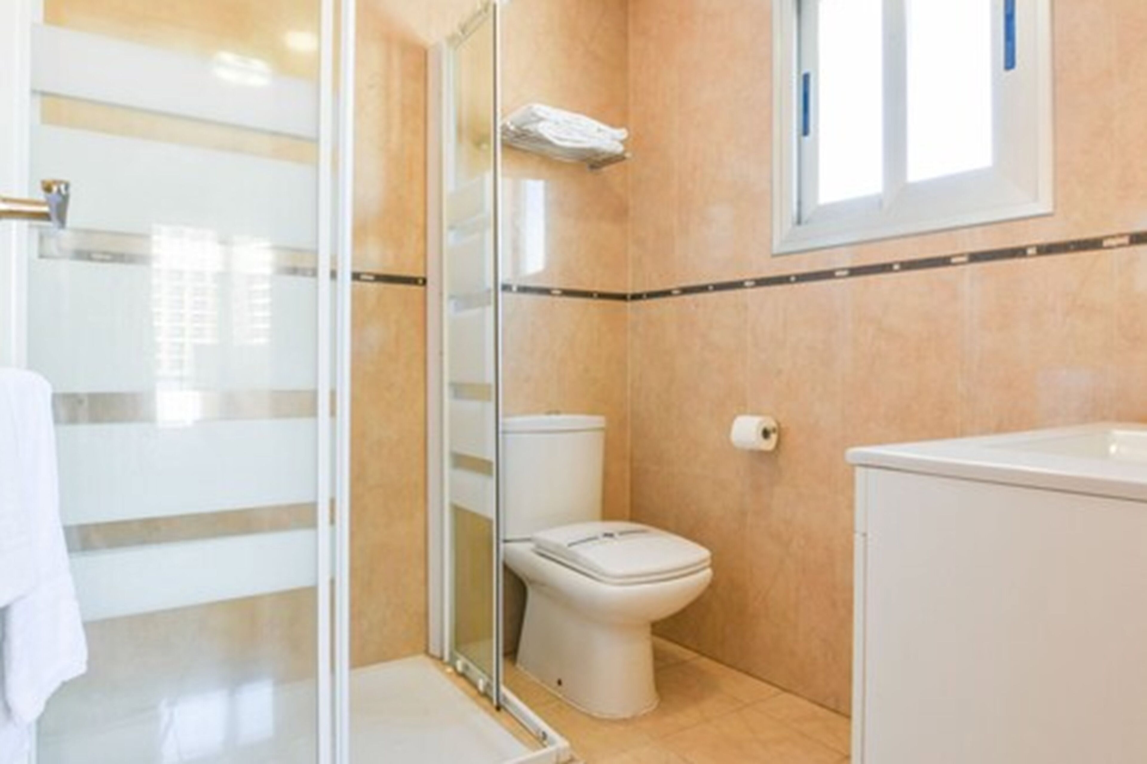 A bathroom with a toilet, a shower enclosure, and a sink.