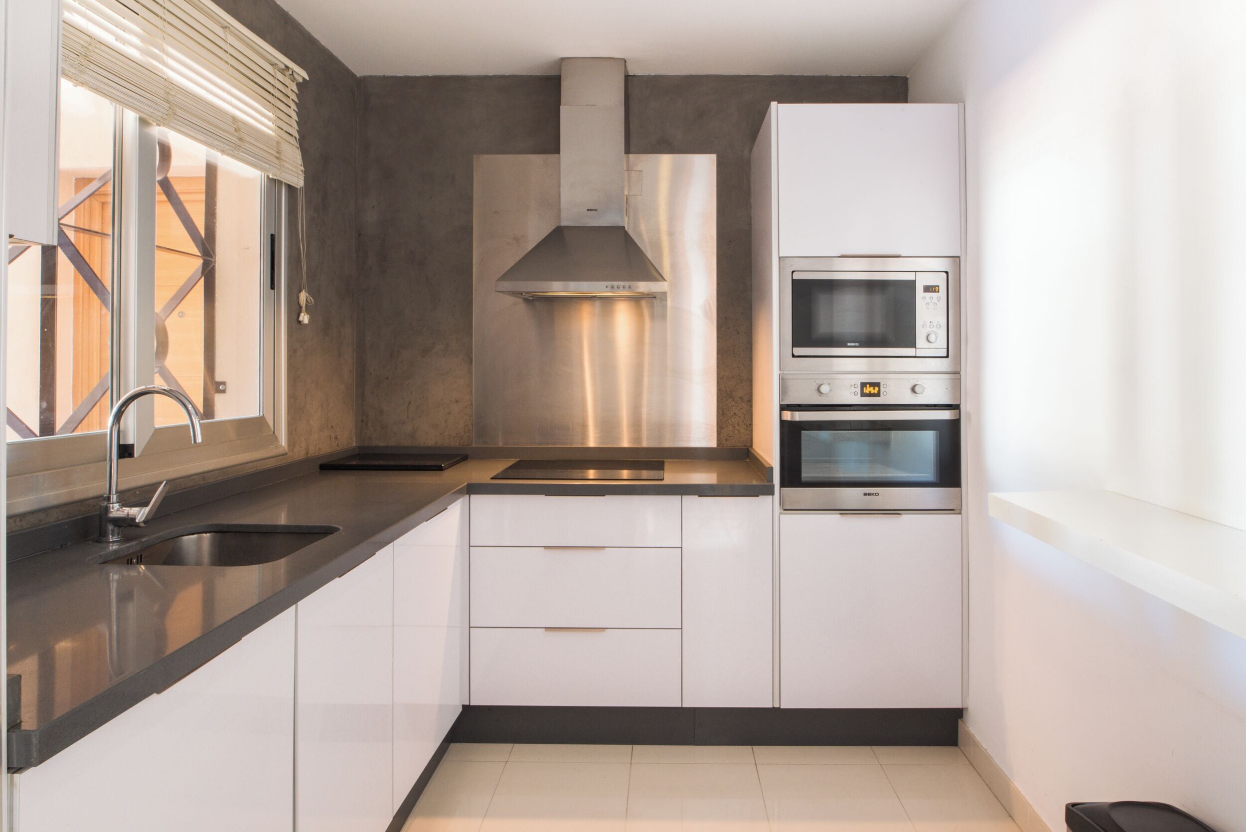 A modern kitchen with a stainless steel range hood, a built-in microwave, and a double oven.