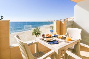 A balcony with a table set for breakfast overlooking a beach. - Apartamentos Vegasol Playa A.T. (Fuengirola)